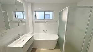 Un baño moderno con una bañera, un lavamanos y una ventana sobre la bañera.