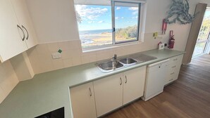 Cocina con vista al exterior, un lavamanos, armarios y un extintor.