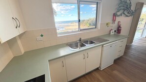 A kitchen with a window view, a sink, cabinets, and a fire extinguisher.