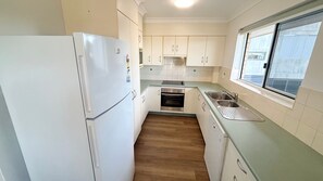 Una cocina compacta con refrigerador, horno, pileta y ventana.