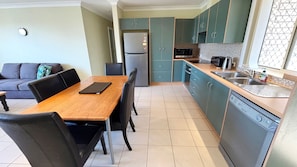 A compact kitchen with a dining table, chairs, a refrigerator, microwave, and a dishwasher.