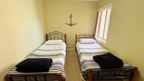 A room with two single beds, a window with a view, and a wall-mounted anchor decoration. - Village Centre 3 - South West Rocks (SOUTH WEST ROCKS)