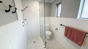 Ein Badezimmer mit einer Duschkabine, einer Toilette und einem Handtuchhalter mit einem Handtuch.