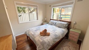 Ein Schlafzimmer mit einem Bett, zwei Nachttischen, einem Fenster und Blick ins Freie.