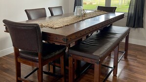 Un espace repas avec une table en bois, des chaises en cuir et un banc.