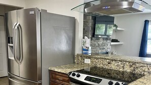 Une cuisine équipée d’un réfrigérateur en acier inoxydable, d’une cuisinière et de plans de travail en granit.