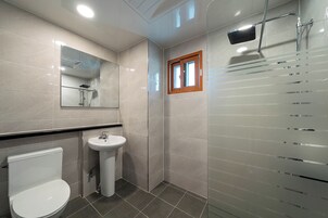 Un baño moderno con inodoro, lavamanos, espejo y ducha.