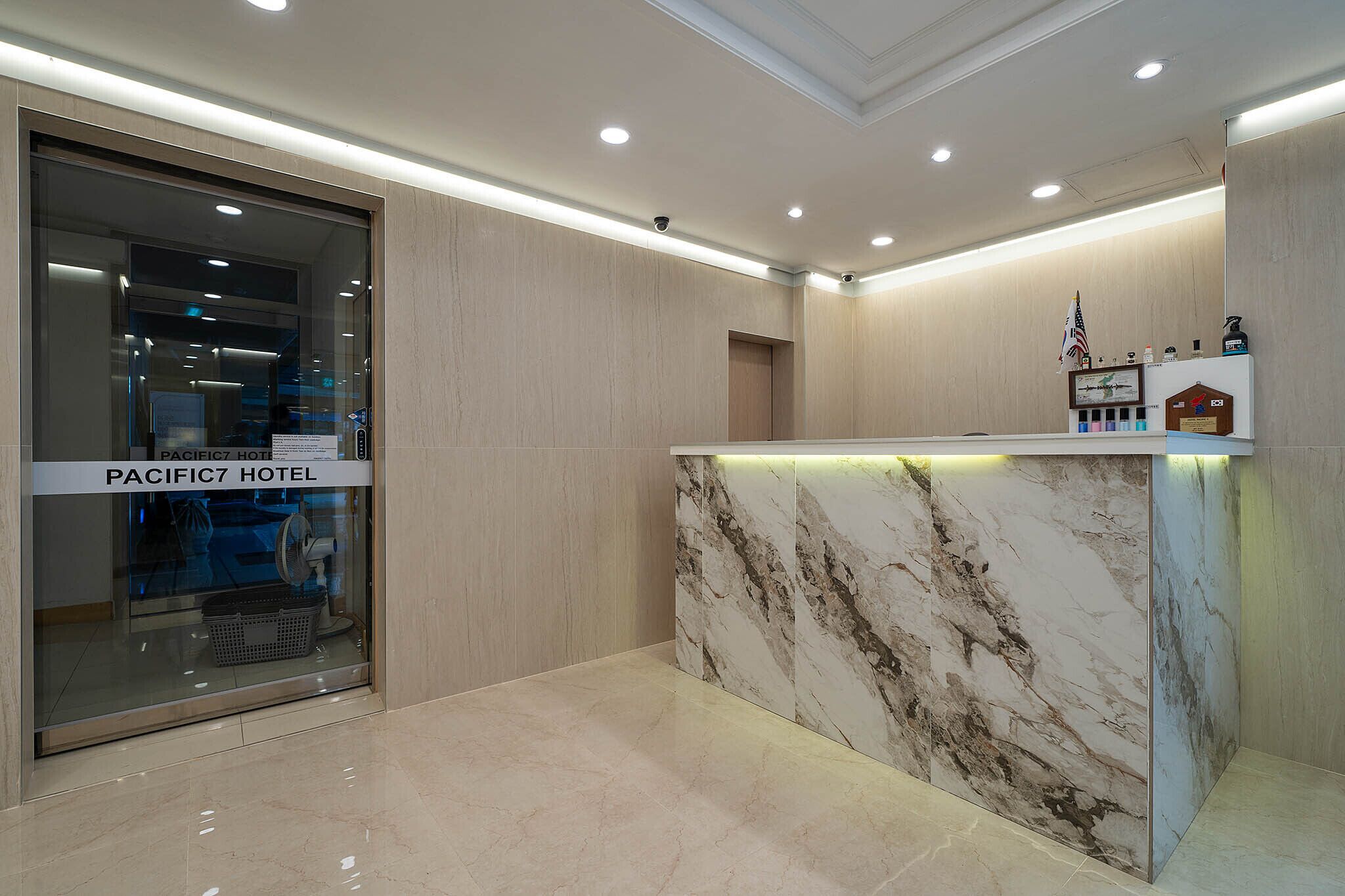 A hotel reception area with a marble counter, a glass door entrance, and a flag.