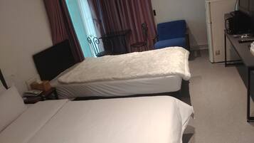 A hotel room with two beds, a desk with a computer, a chair, and a small table.