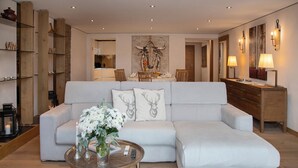 A modern living room with a sectional sofa, a glass coffee table, and a decorative wall piece. - Chesa Piz Padella - St. Moritz by Interhome (St. Moritz)
