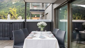 A table set for four on an outdoor patio with wicker chairs, a white tablecloth, and a vase of white flowers. - Chesa Piz Padella - St. Moritz by Interhome (St. Moritz)