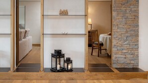 A modern interior with a wooden floor, a stone wall, and a glass partition with shelves. - Chesa Piz Padella - St. Moritz by Interhome (St. Moritz)