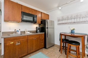 A kitchen with wooden cabinets, a stainless steel refrigerator, a microwave, and a coffee maker.