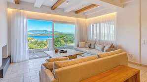Un salón amplio con un gran ventanal corredera que da a un balcón con vistas panorámicas.