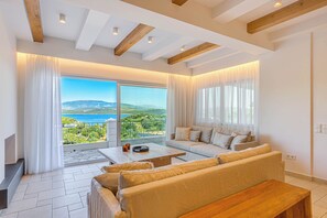 A spacious living room with a large sliding glass door leading to a balcony with a scenic view.