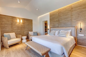 Une chambre moderne avec un grand lit, un banc, un canapé et un mur d’accent en bois.