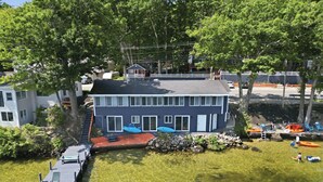A two-story building with a dock extending into a clear body of water, surrounded by trees and other buildings. - NEW Lakefront Escape Private Dock & Lake Views (Alton)