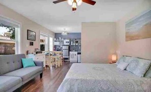 Un dormitorio con cama, sofá y una kitchenette al fondo.