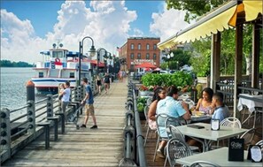 A pier with tables and chairs, a boat docked in the background, and a building with a sign. - 2 HOUSES!! Dreamy Villa & Tiny House! Large pool! (Wilmington)