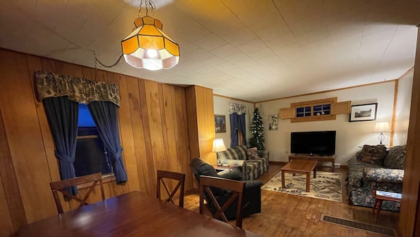 Una sala acogedora con una mesa de comedor de madera, un sofá, un televisor y un árbol de Navidad.