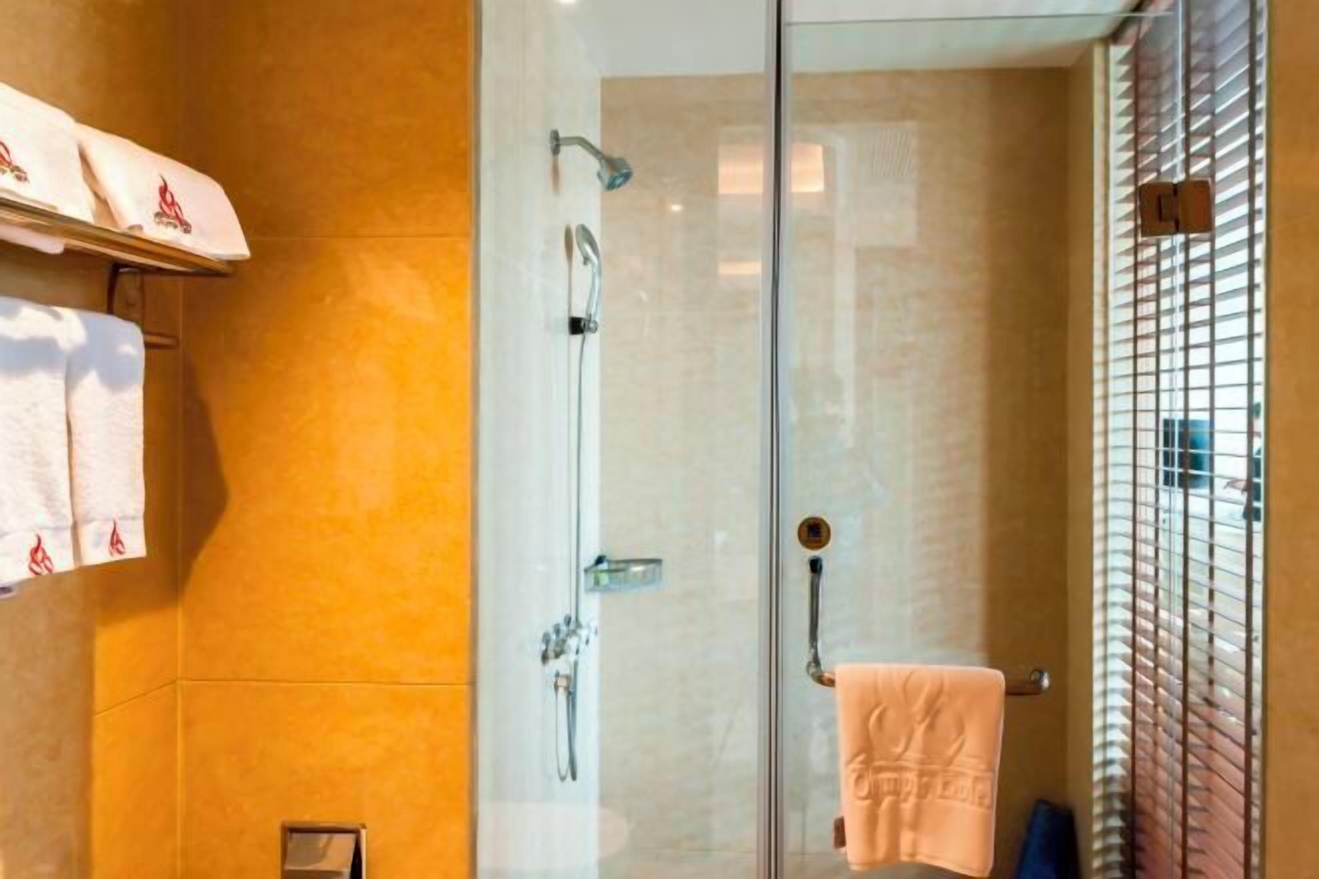 Ducha con cerramiento de vidrio, un perchero y puerta de vidrio.