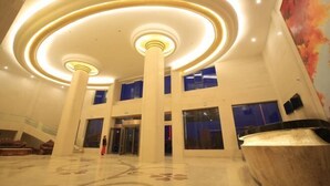 Um hall amplo com teto alto, luminárias circulares e um balcão de recepção espaçoso.