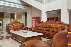 A lobby with leather sofas and a marble coffee table. - Aoti Hotel (Wuhu)