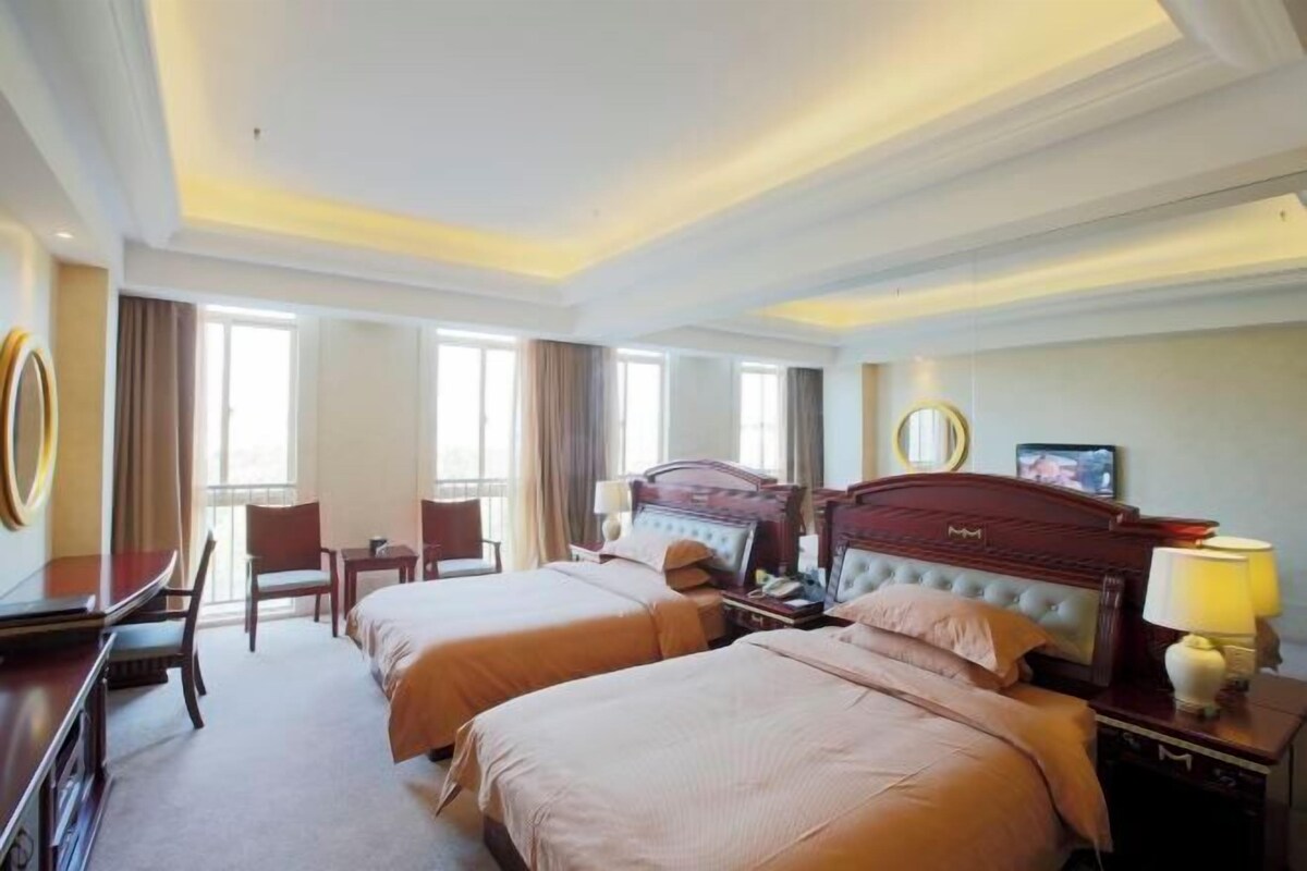Ein Hotelzimmer mit zwei Betten, einem Schreibtisch und einem Sessel.
