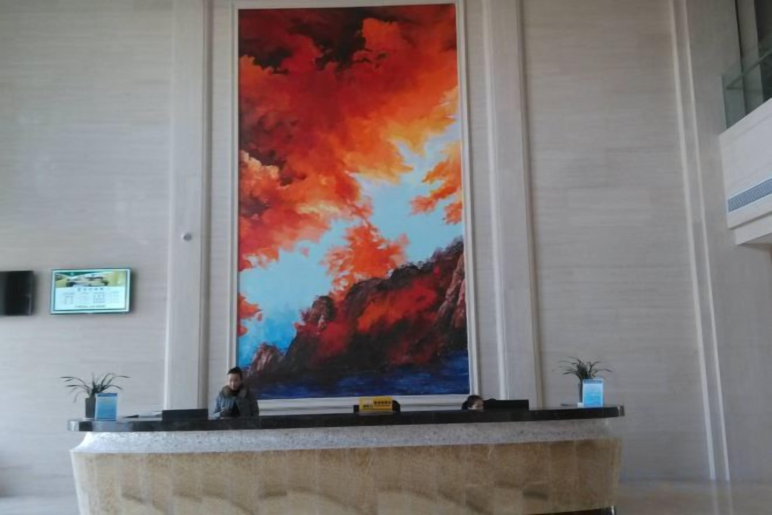A reception desk with a large abstract painting on the wall behind it.