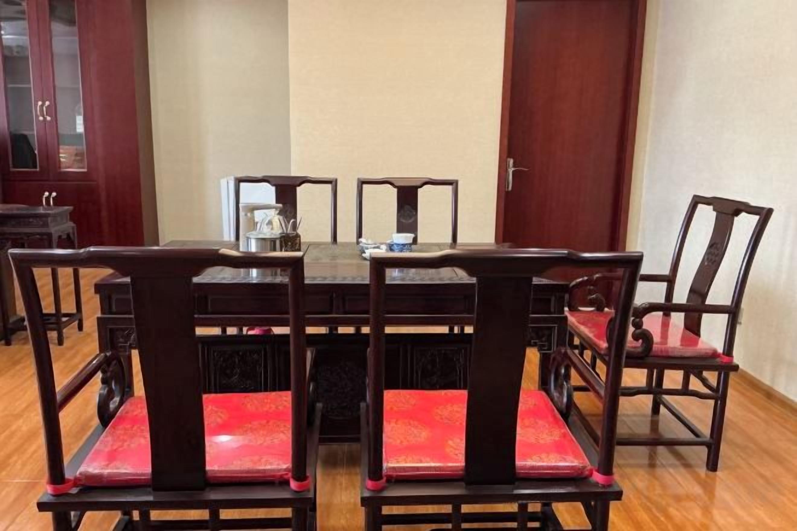 A dining table with six chairs, a coffee pot, and a small table in the center.