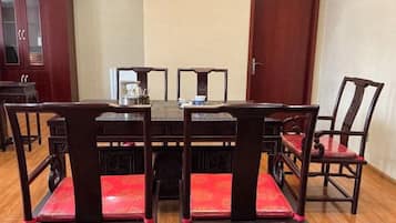 A dining table with six chairs, a coffee pot, and a small table in the center.