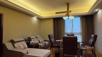 Una habitación de hotel con sofá, sillas, mesa de comedor y candelabro.