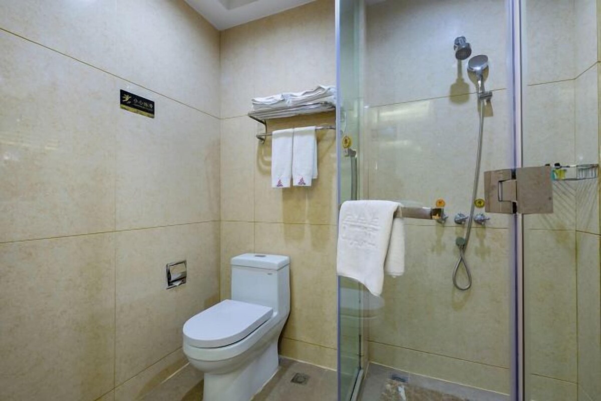 Ein Badezimmer mit Toilette, Duschkabine und Handtuchhalter.