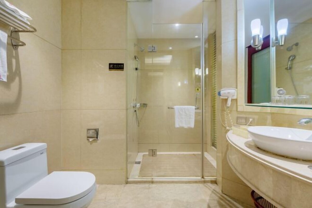 Ein modernes Badezimmer mit einer Duschkabine aus Glas, einer weißen Toilette und einem großen Spiegel mit Beleuchtung.