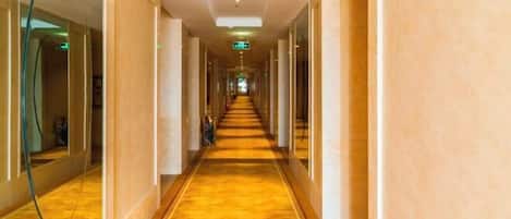 A long, narrow hallway with a polished wooden floor and beige walls.