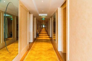 A long, narrow hallway with a polished wooden floor and beige walls.