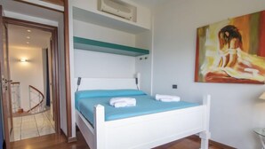 Ein Schlafzimmer mit einem weißen Bett, einer blauen Tagesdecke und einem Bild an der Wand.