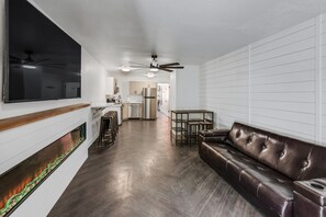 A modern living room with a dark leather sofa, a flat-screen TV mounted on the wall, and a fireplace with a glass enclosure. - Beautiful Ski-in/ski-out Condo Located On The Eagle Point Resort! 1 Bedroom Condo by RedAwning (Beaver)