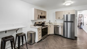 A modern kitchen with white walls, wooden cabinets, stainless steel appliances, and a herringbone wood floor. - Beautiful Ski-in/ski-out Condo Located On The Eagle Point Resort! 1 Bedroom Condo by RedAwning (Beaver)