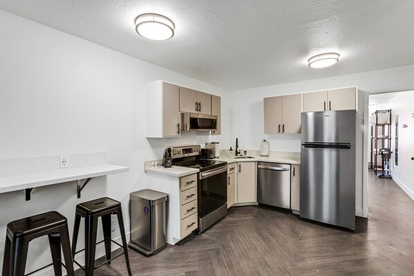 A modern kitchen with white walls, wooden cabinets, stainless steel appliances, and a herringbone wood floor. - Beautiful Ski-in/ski-out Condo Located On The Eagle Point Resort! 1 Bedroom Condo by RedAwning (Beaver)