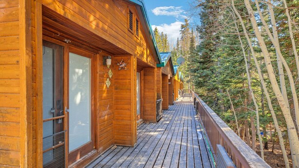 A wooden cabin with a deck, surrounded by trees. - Beautiful Ski-in/ski-out Condo Located On The Eagle Point Resort! 1 Bedroom Condo by RedAwning (Beaver)