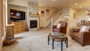 A living room with a fireplace, a television, and a staircase. - Prospector Point E 4br 3.5ba 4 Bedroom Townhouse by RedAwning (Frisco)
