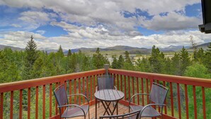 A wooden deck with a table and chairs, overlooking a mountainous landscape with trees and a clear sky. - Prospector Point E 4br 3.5ba 4 Bedroom Townhouse by RedAwning (Frisco)