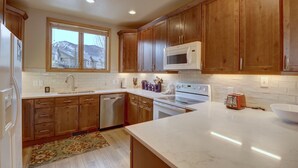 A modern kitchen with wooden cabinets, a microwave, an oven, and a dishwasher. - Prospector Point E 4br 3.5ba 4 Bedroom Townhouse by RedAwning (Frisco)
