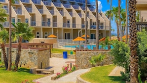 Un hotel con varios balcones, piscina y palmeras.