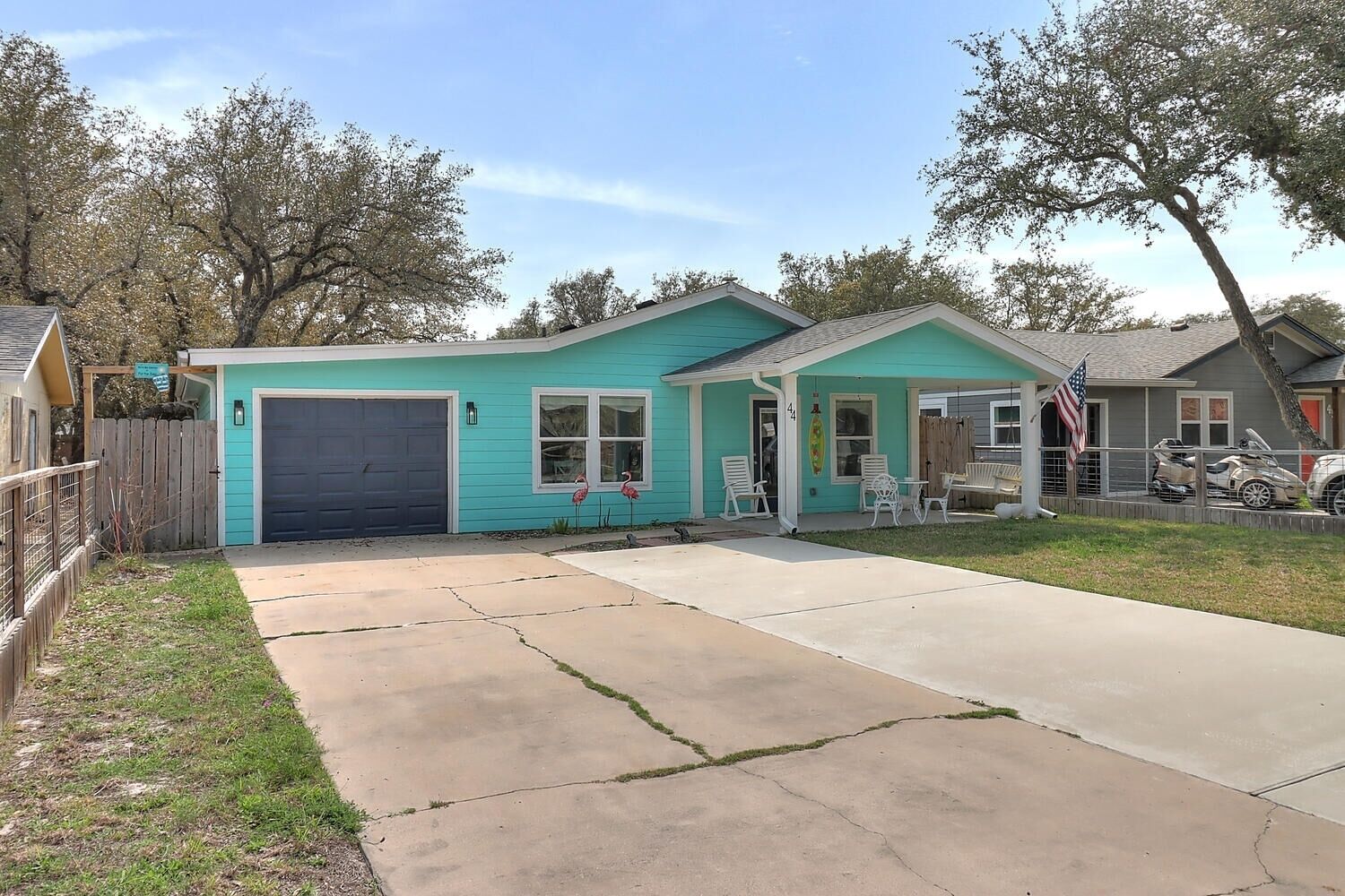 A single-story house with a garage, a front porch with chairs, and a small garden.