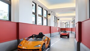 A hallway with two sports cars parked, red walls, and large windows. - CHECK inn MAGI Kids (Luodong)