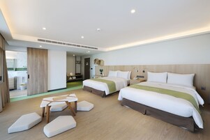Una habitación de hotel con dos camas, una mesita y un banco.