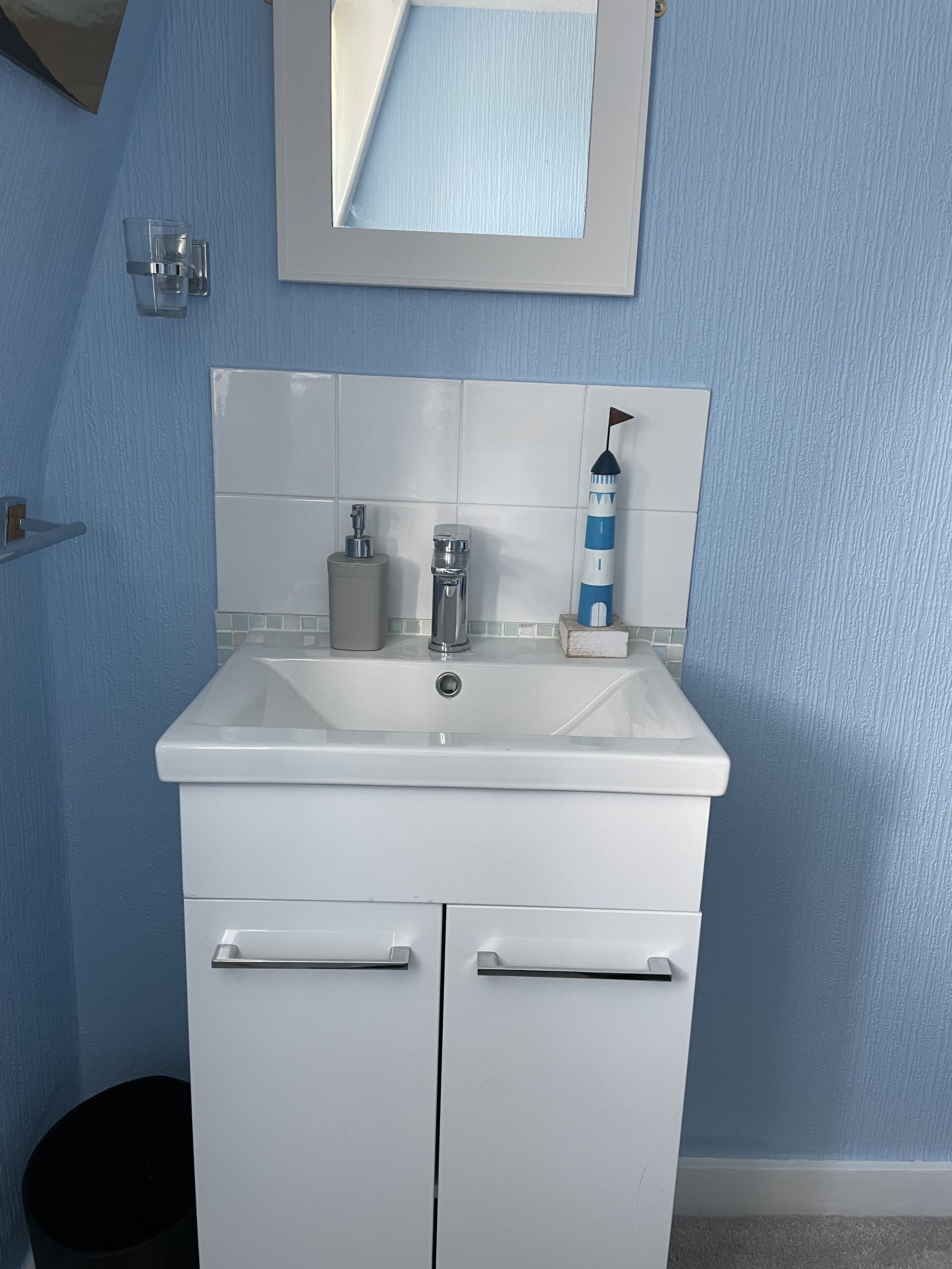 A bathroom with a white sink, a mirror, and a blue wall.