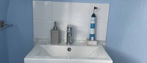 A bathroom with a white sink, a mirror, and a blue wall.